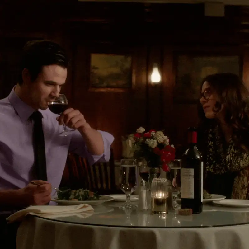 A couple enjoying an intimate dinner with wine and candlelight in an elegant restaurant setting.