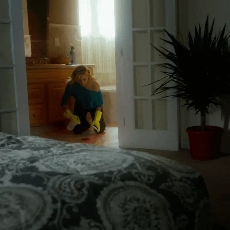 Woman cleaning bathroom floor with gloves in a cozy home setting.