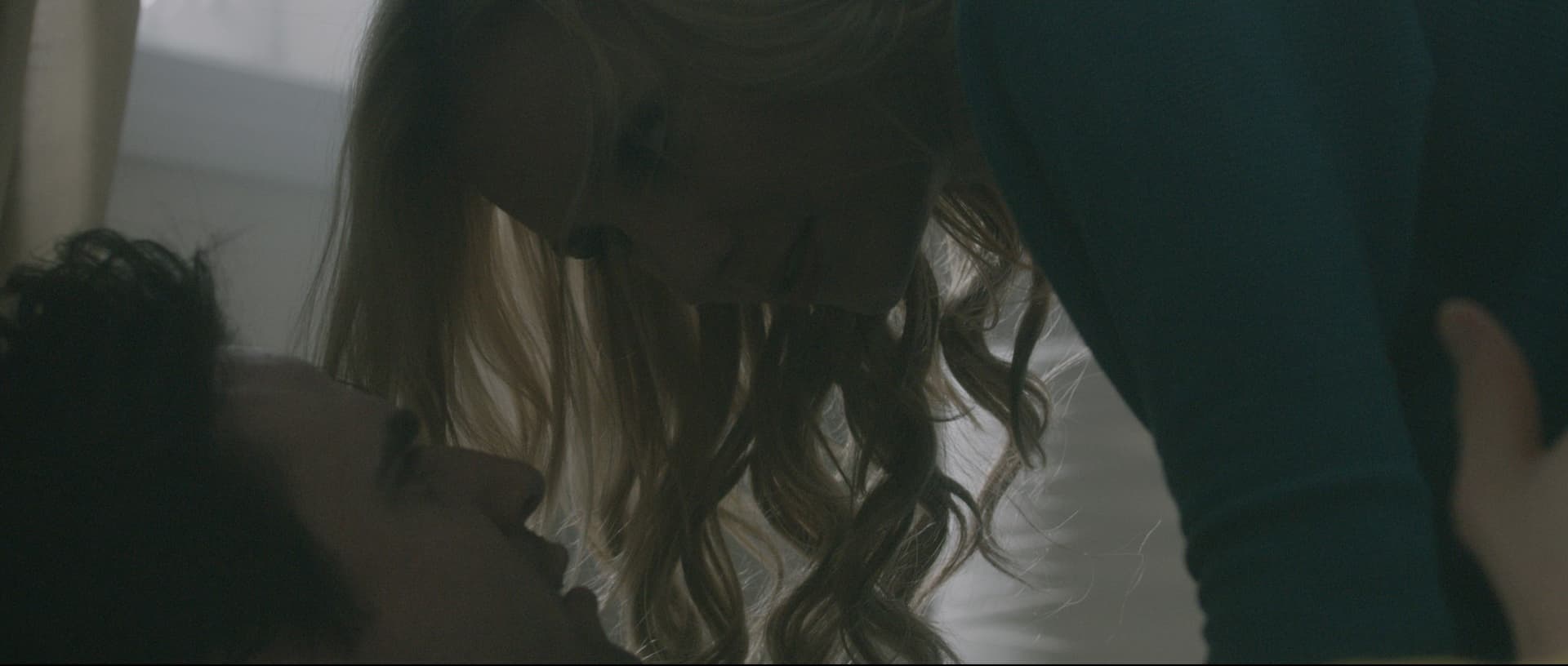 Two figures share an intimate moment indoors, emphasizing emotions and connection.