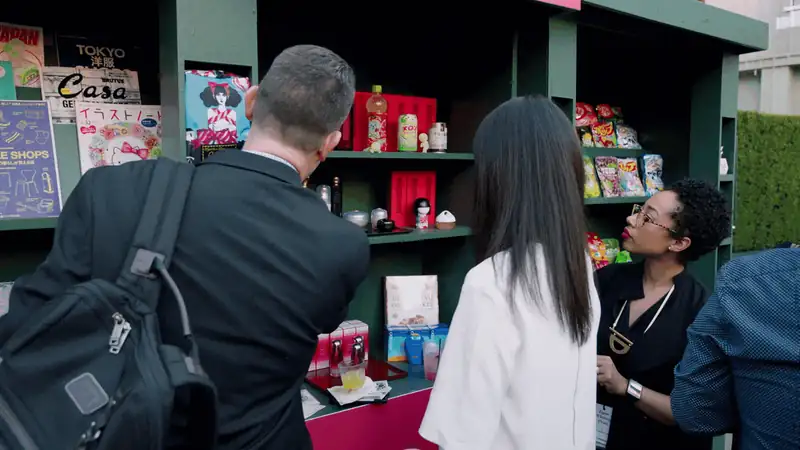 People exploring a colorful display of snacks and beverages at an outdoor event.