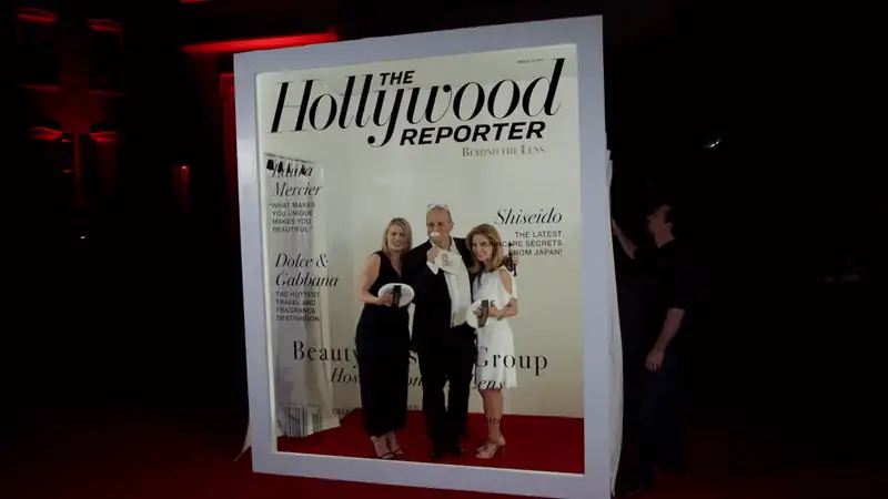 Group posing in front of a giant The Hollywood Reporter magazine cover at an event.