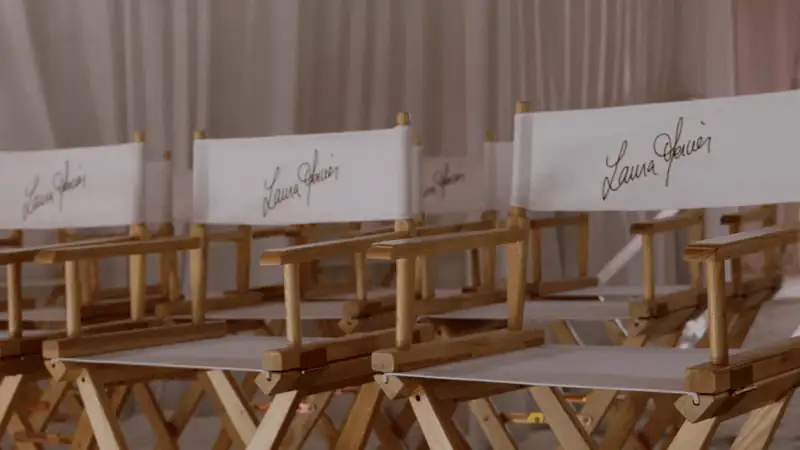 Row of director's chairs with the name 'Laura Mercier' on white canvas, set against a soft backdrop.