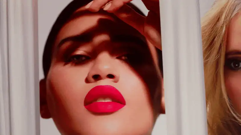 Dramatic portrait of a woman with bold red lips and shadows, showcasing beauty and fashion aesthetics.