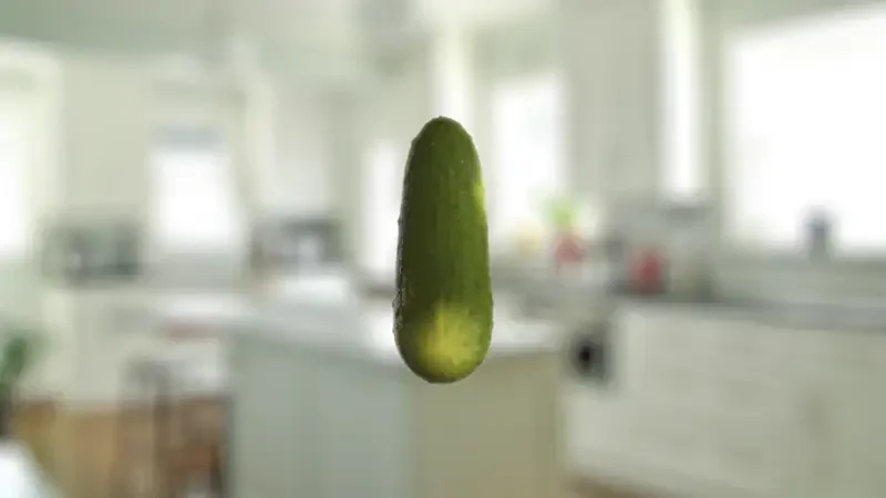 An isolated cucumber floating in a bright modern kitchen setting.