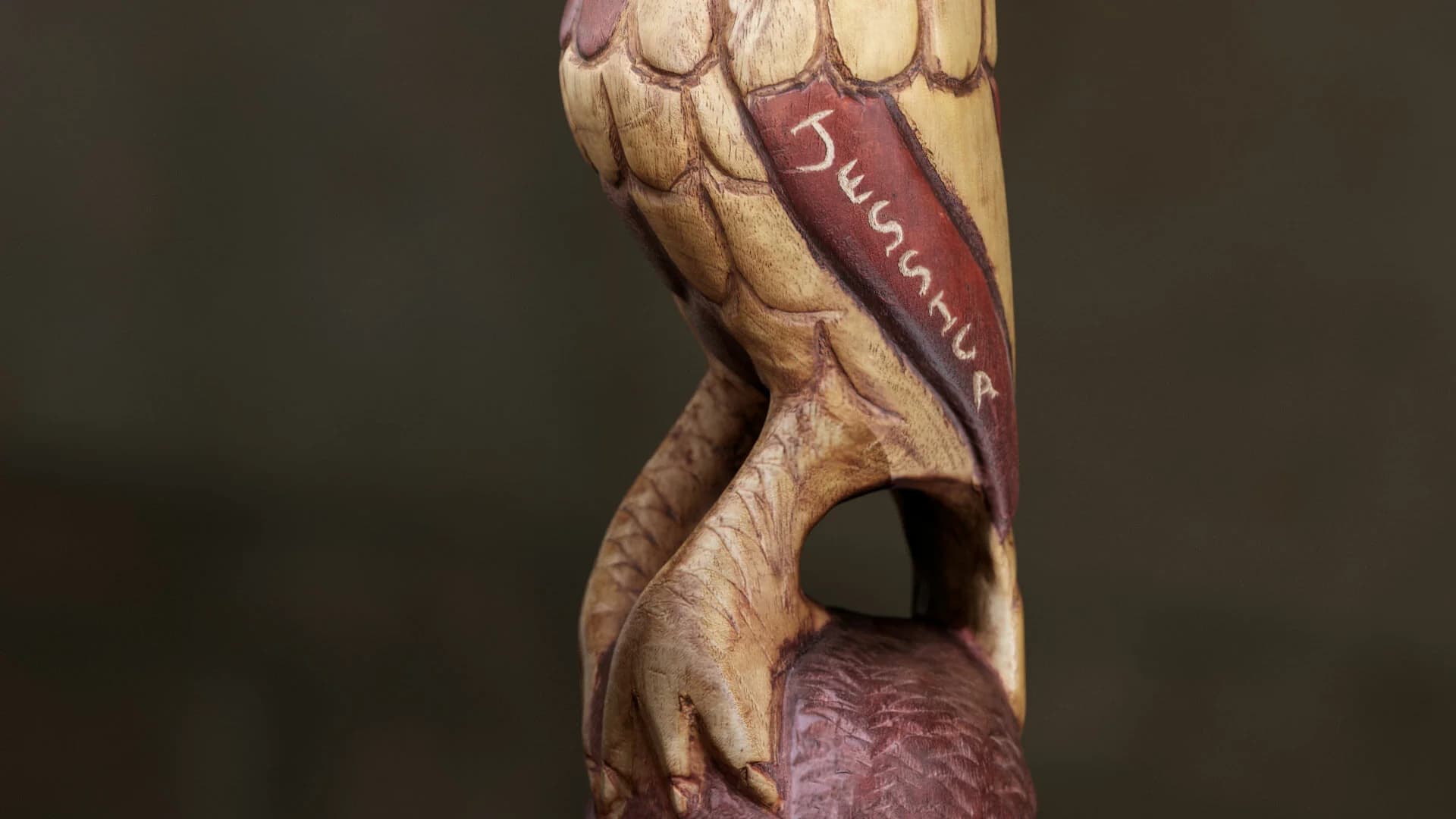 Intricate wooden sculpture of a bird with detailed feathers and engraved markings.