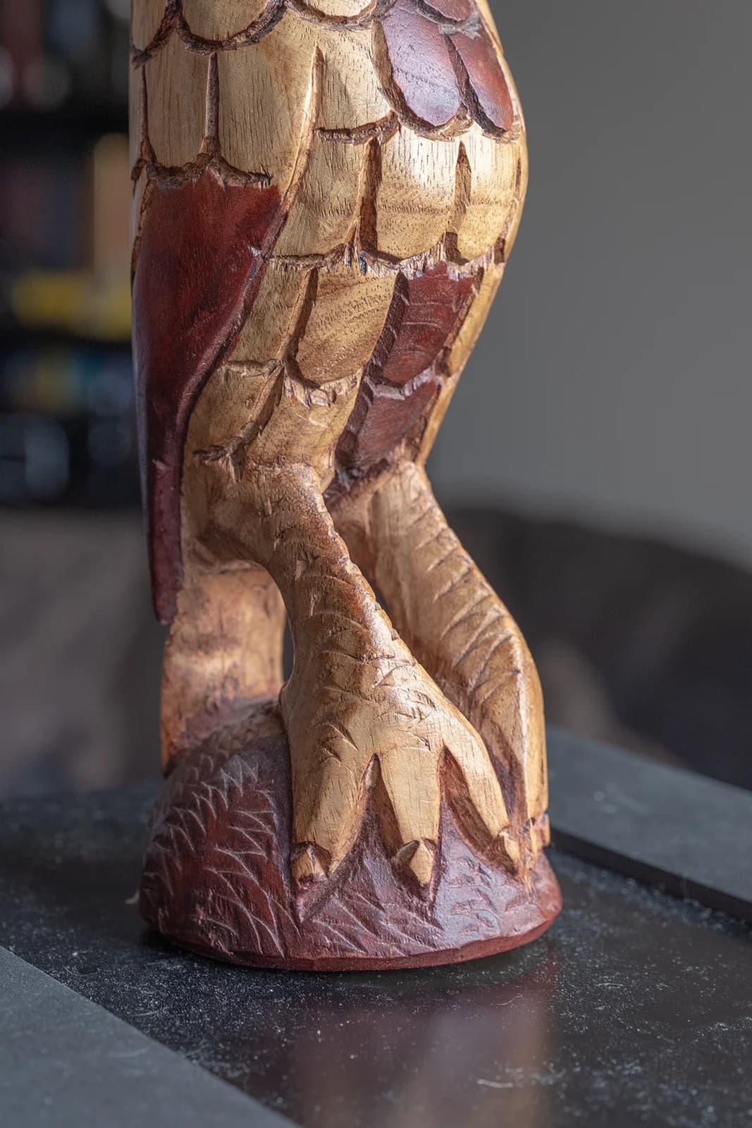 Close-up of intricately carved wooden owl feet on a textured base.