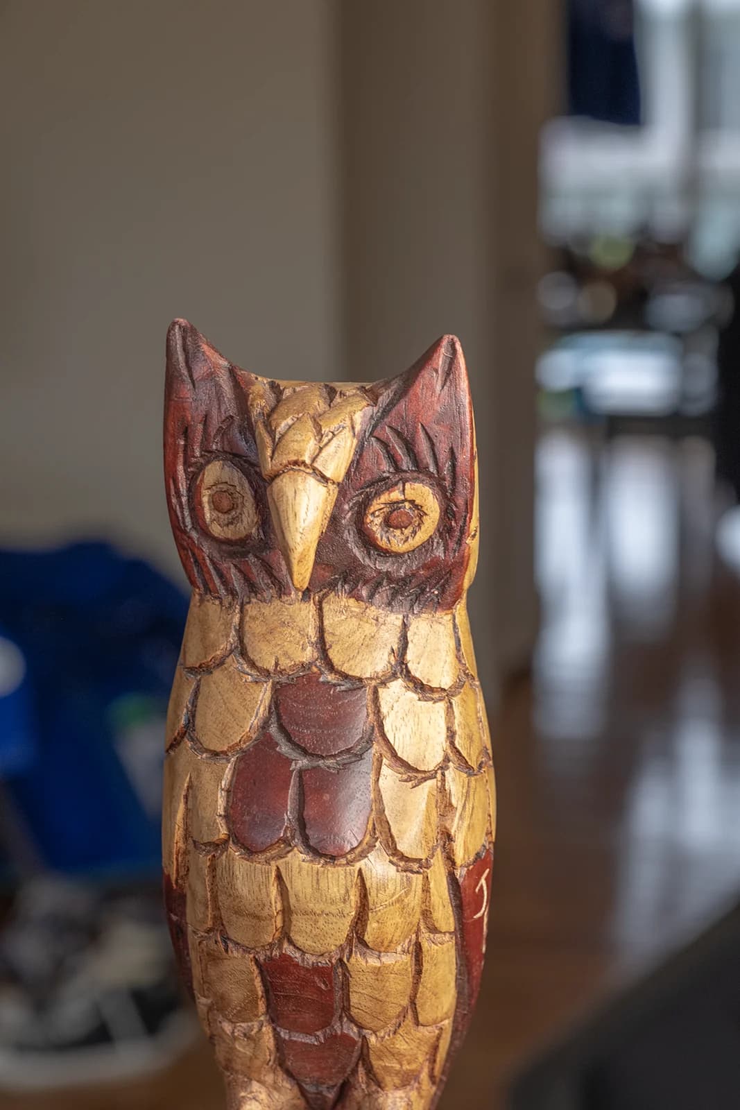 Detailed wooden owl sculpture with intricate carvings and vibrant colors, displayed indoors.