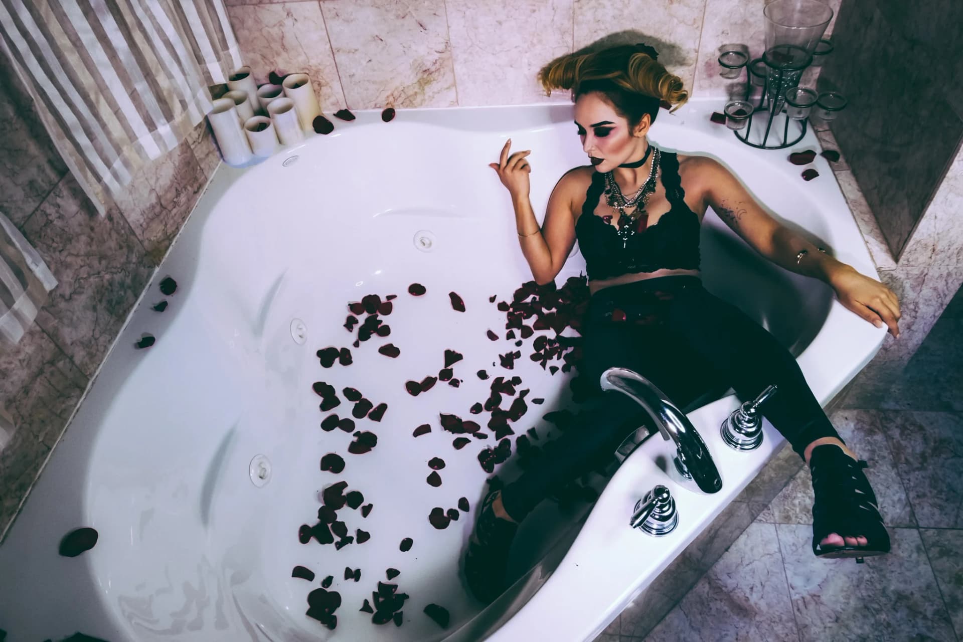A woman in a bathtub filled with rose petals, creating a dramatic and luxurious atmosphere.