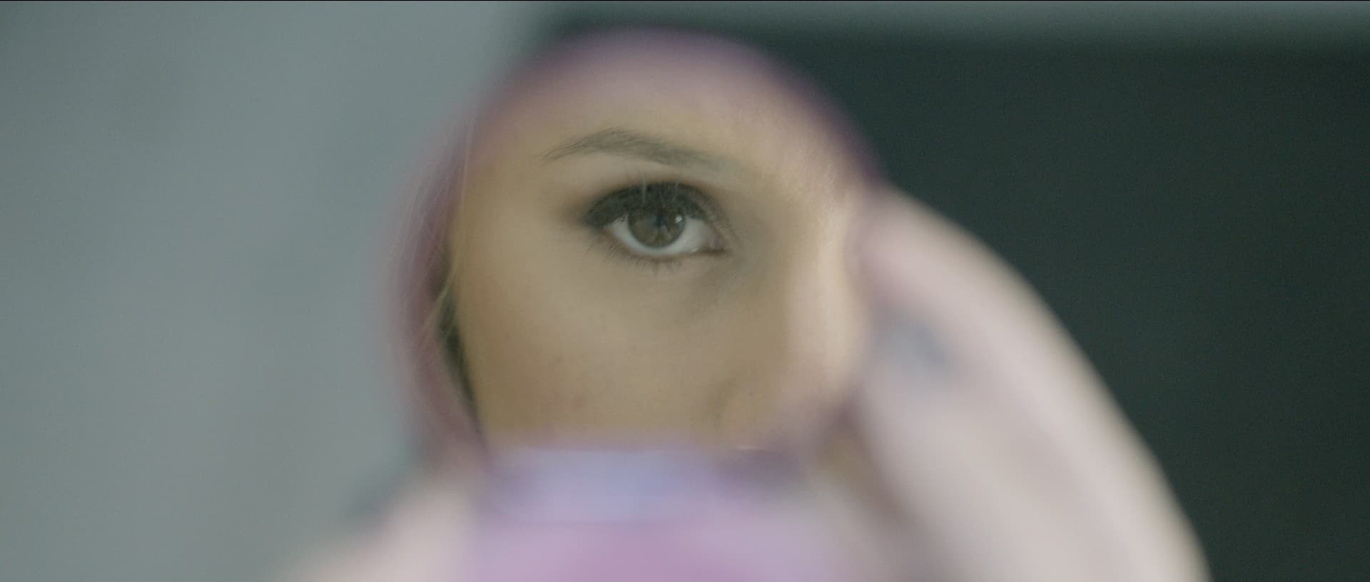 Close-up of a woman’s eye reflected in a circular mirror, showcasing intricate details and vivid colors.