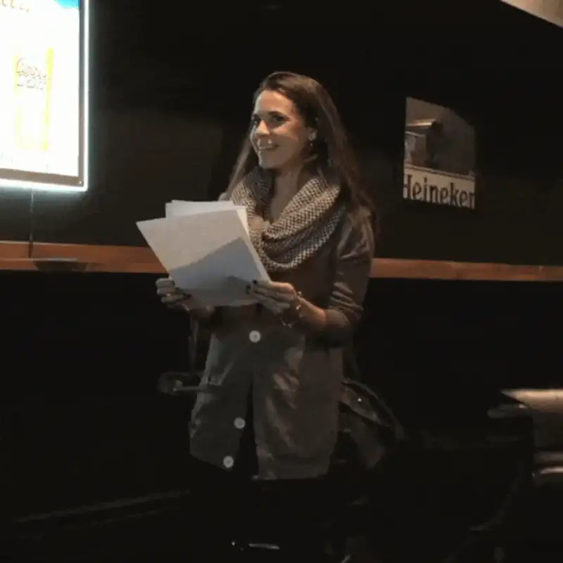 Woman presenting with papers in a cozy venue with a bar atmosphere and soft lighting.