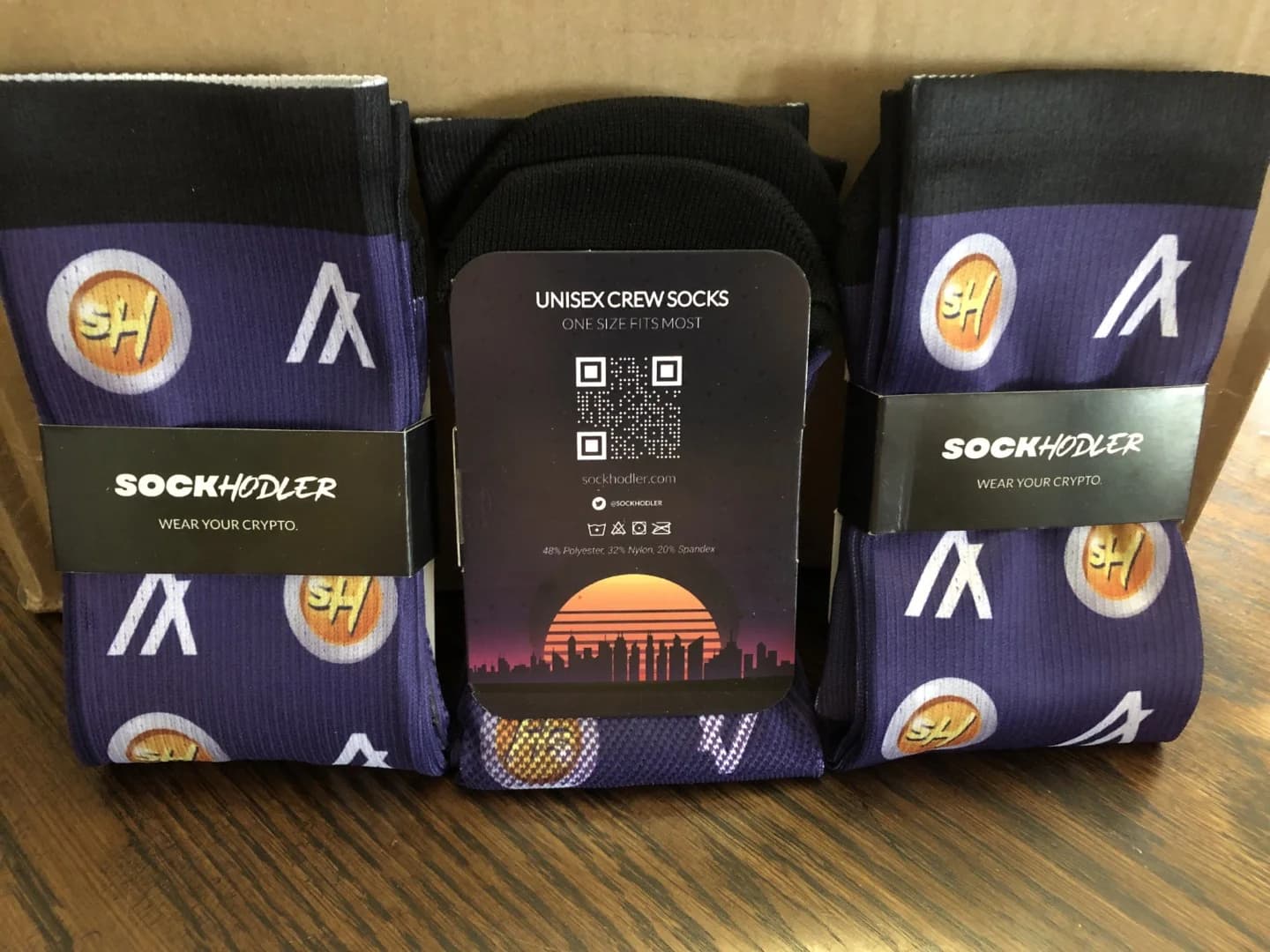 Pair of purple unisex socks with crypto-themed designs and packaging.