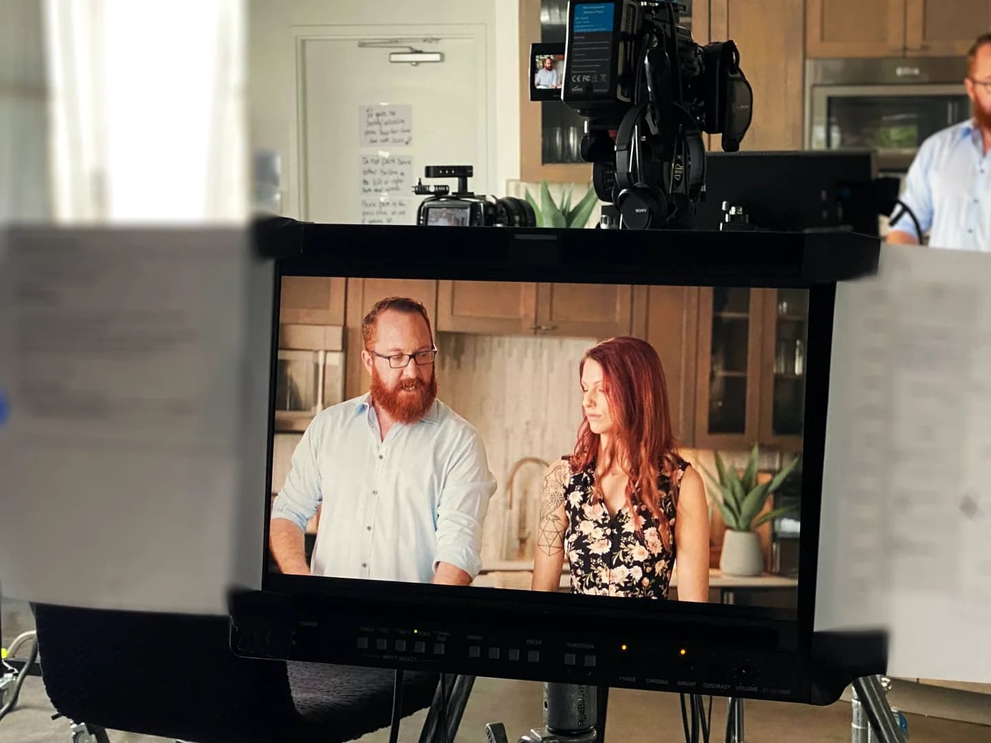 Filming a cooking segment with a man and woman in a modern kitchen setting.