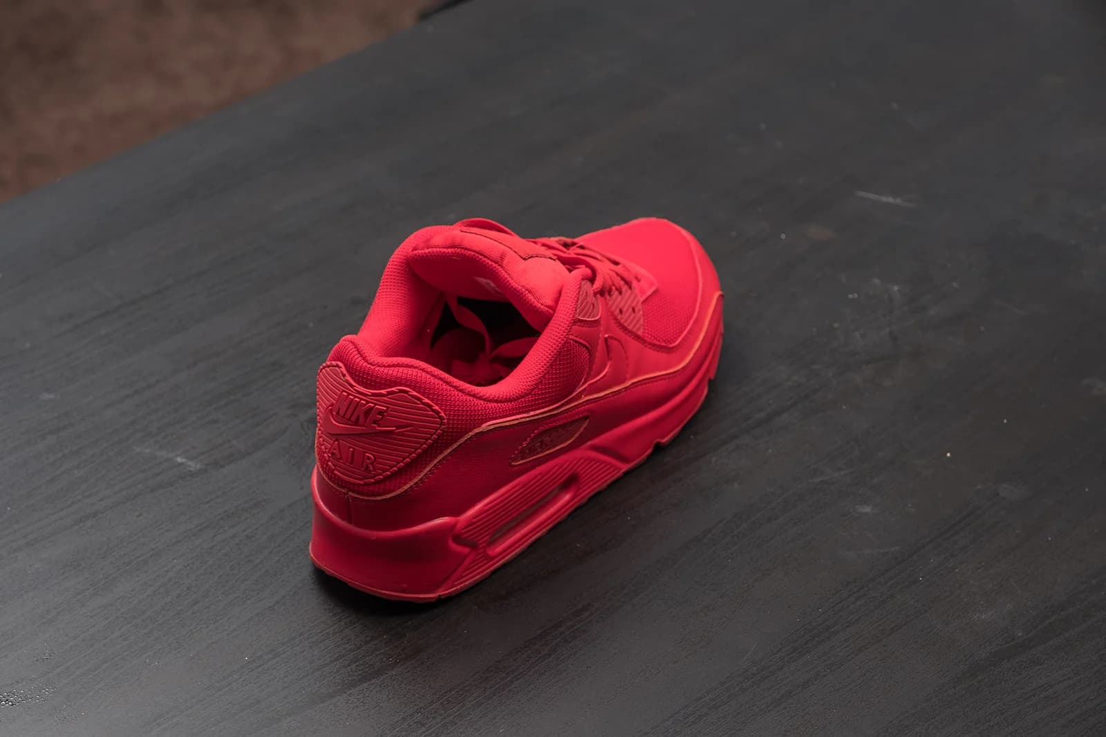 Red Nike Air sneaker on a dark wooden surface, showcasing its stylish design and comfort.