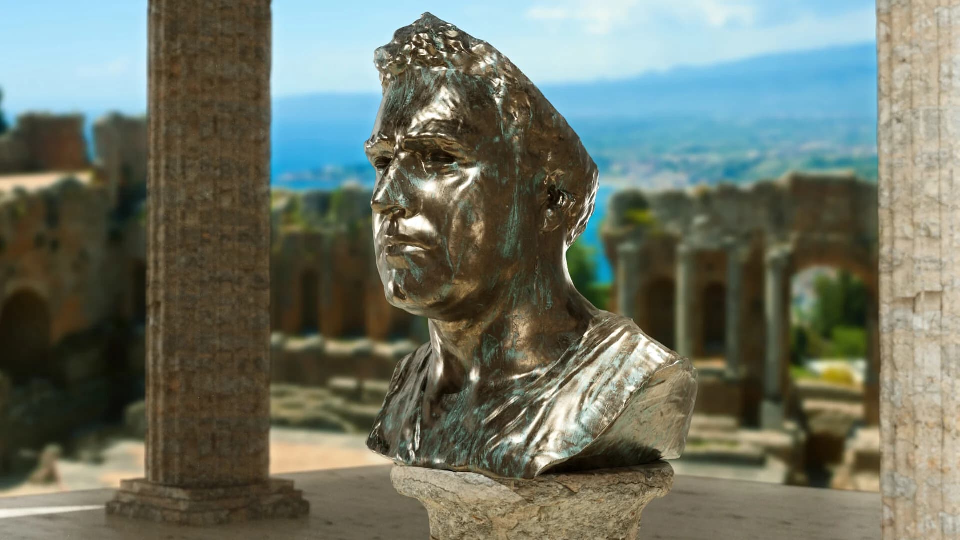 Bronze sculpture bust of a man set against a scenic ancient ruins background